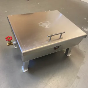 Metal grill or barbecue with a lid and side handle on a gray surface.